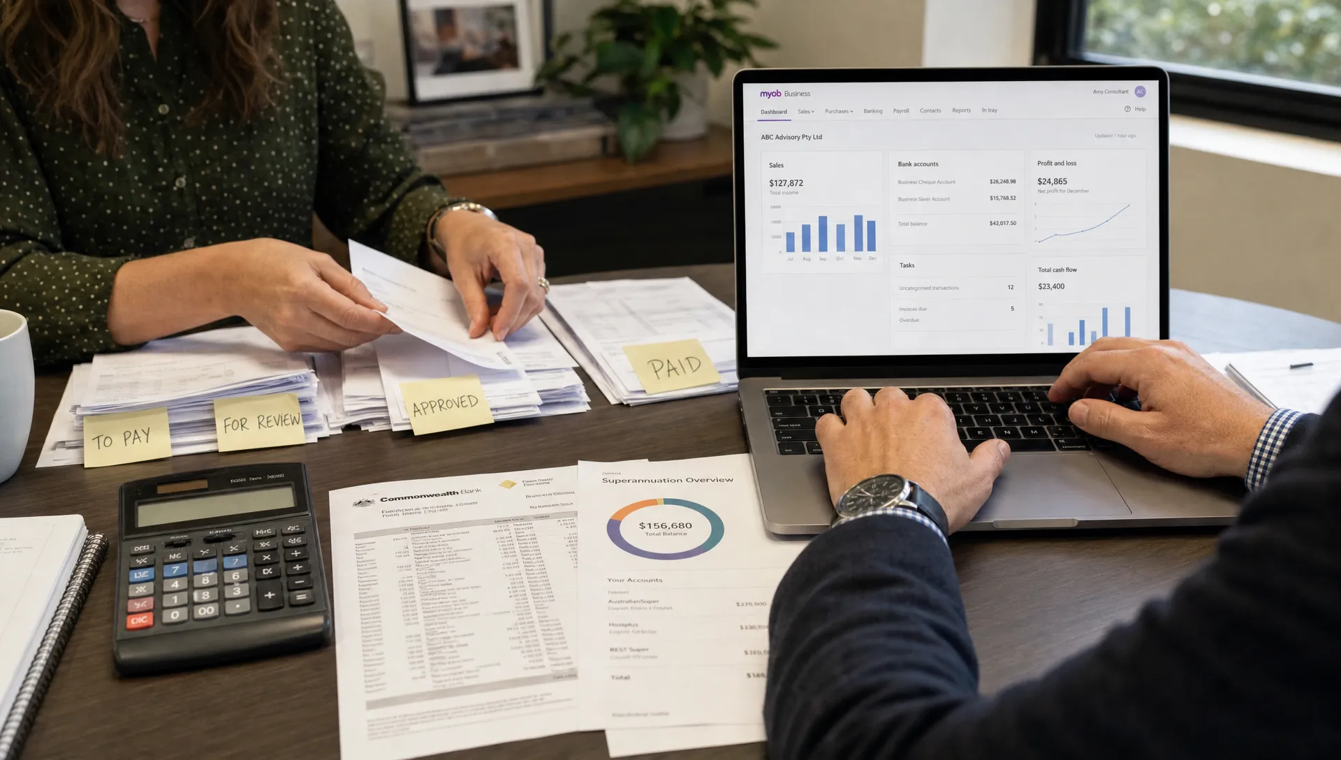 Hands sort invoices and enter figures into cloud accounting software before a business tax consultation.